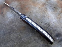 Couteau LOU PALOUMAYRE manche en ébène avec guillochage du ressort, du dos de la lame ainsi que les vis de serrage.