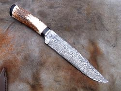 Dague de chasse avec manche en bois de cerf et lame en damas forgé.