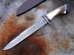 Dague de chasse avec manche en bois de cerf et lame en damas forgé.